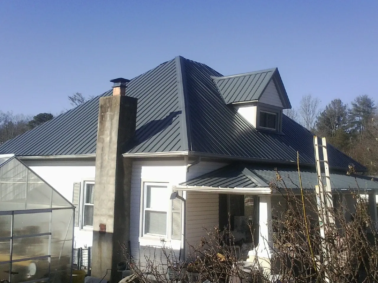 Dark blue standing seam metal roof on a white farmhouse with dormer — Slate & Tile Roof Repair by Roofing Brothers in Quinault