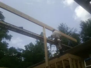 Carpenter setting a ridge beam over a new addition frame — Ice Dam Removal by Roofing Brothers in Quinault