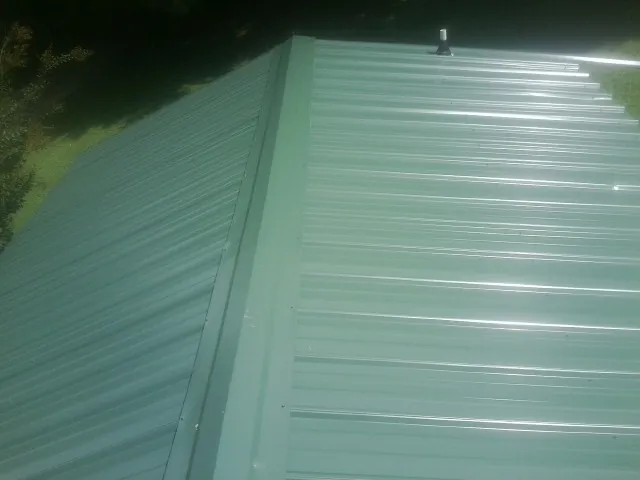 New green metal panels meeting at the ridge of a roof — Flat Roof Repair work by our crew in Quinault