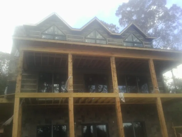 Dormers and porch framing on a large log home under construction — Roof Coating work by our crew in Quinault