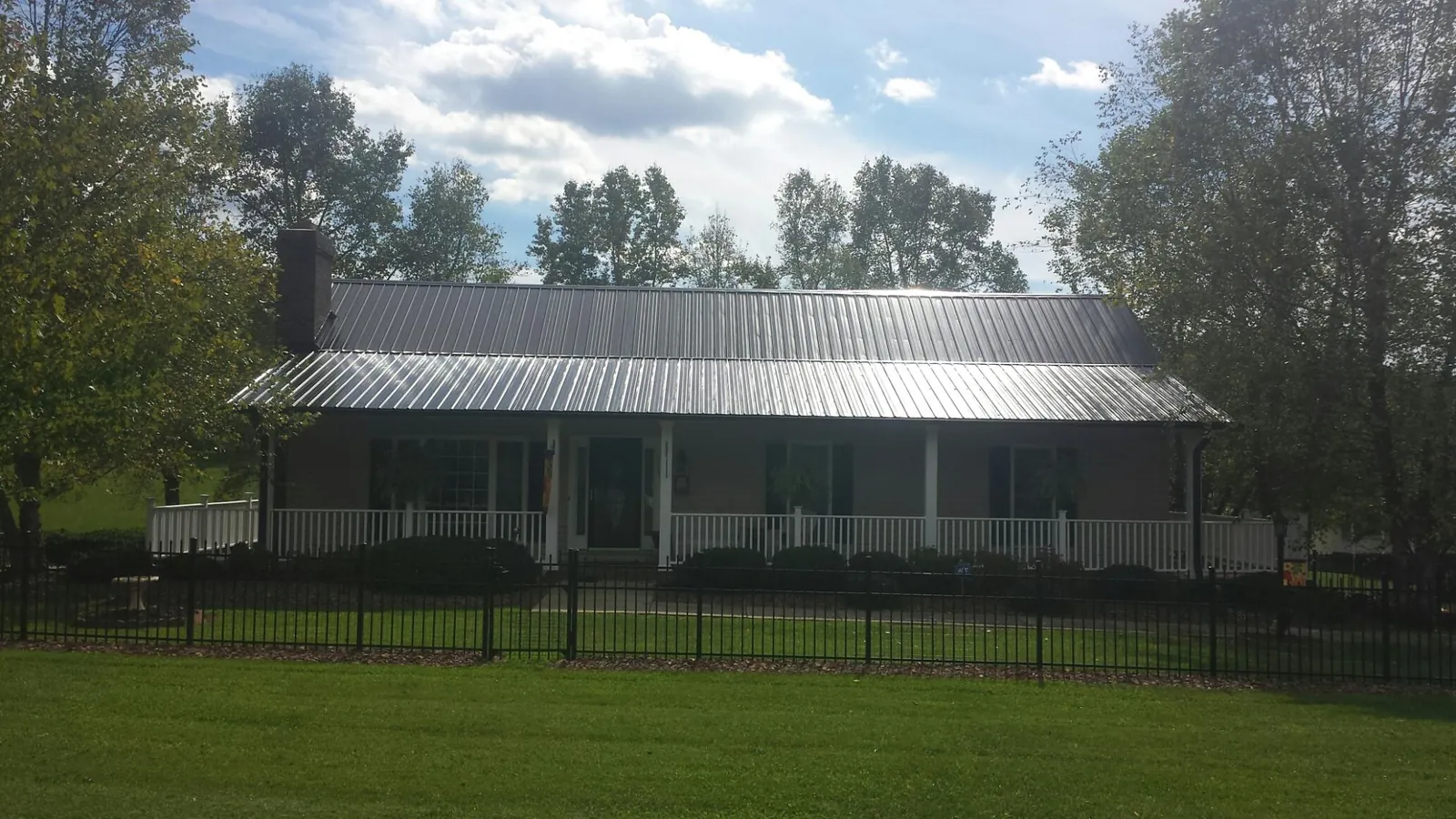 Gray metal roof on a brick ranch with a full width front porch — Gutter Guard Installation work by our crew in Quinault