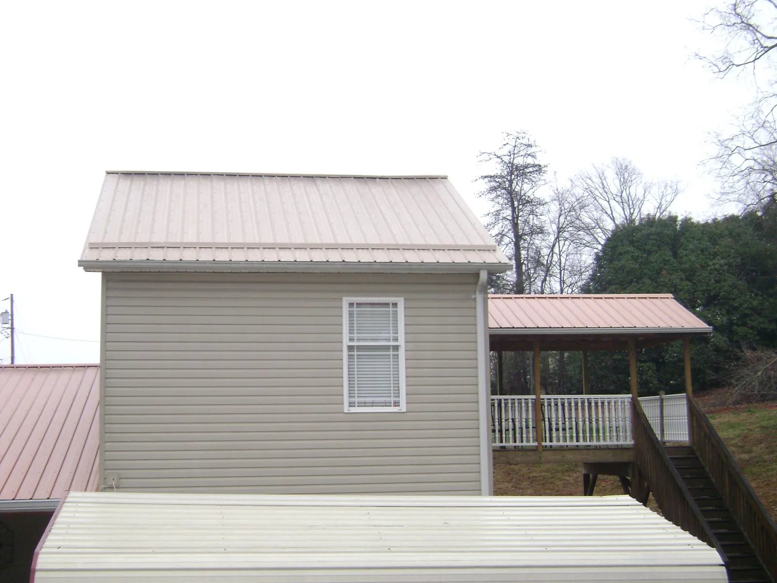 Tan metal roofs on a two story addition and attached porch, from a Roof Replacement job in Quinault