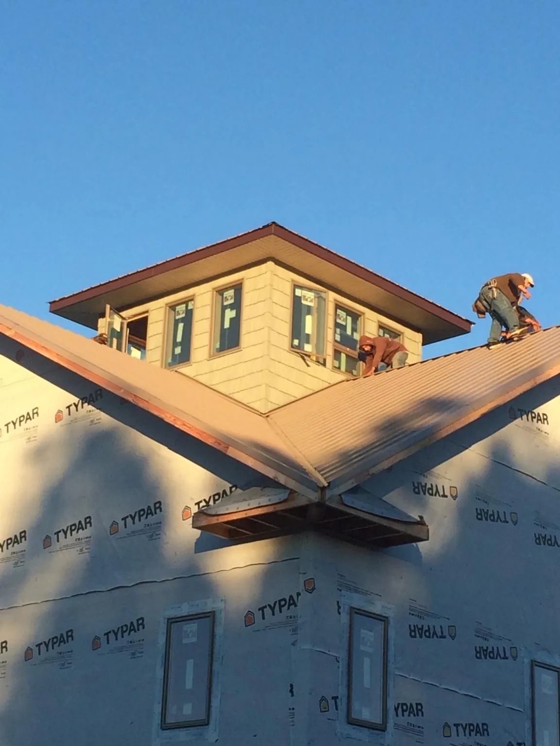 Roofers working around a rooftop cupola on a new metal roof at sunset — Roof Waterproofing in Quinault by Roofing Brothers